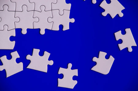 Broken pieces of jigsaw puzzles on blue backgroundの写真素材