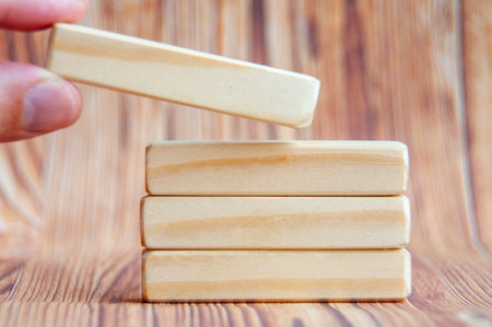 Hand placing wooden blocks on other wooden blocks with customizable space for textの写真素材