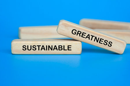 Wooden block on blue background showing SUSTAINABLE GREATNESS text for long-term stabilityの写真素材