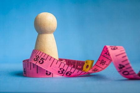 Wooden peg beside pink measuring tape showing healthy lifestyle theme with customizable space for...