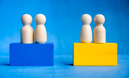 Four wooden pegs on a yellow and blue blocks symbolizing inclusion and leadership.の写真素材