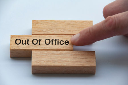 Out of office text on wooden blocks with hand pushing it. Getaway or on a vacation concept