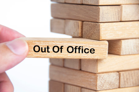 Hand pulling out wooden block with out of office text on it. Getaway or on a vacation concept