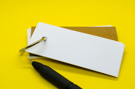 White banner shape notepad with customizable space for text on yellow cover background and a pen.の写真素材