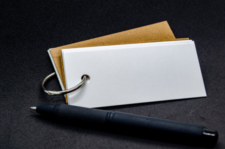 White banner shape notepad with customizable space for text on black cover background and black pen....