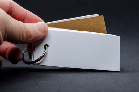 Hand holding white banner shape notepad with customizable space for text on black cover backgroundの写真素材