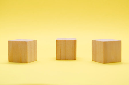 Close up view of isolated wooden cube with customizable space for text or ideas on yellow background.の写真素材