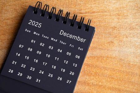 Top view of black December 2025 calendar on wooden cover background. Year end concept.の写真素材