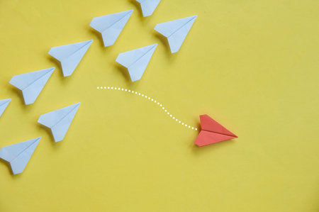 Red airplane leaving the rest of the white airplanes on yellow cover background