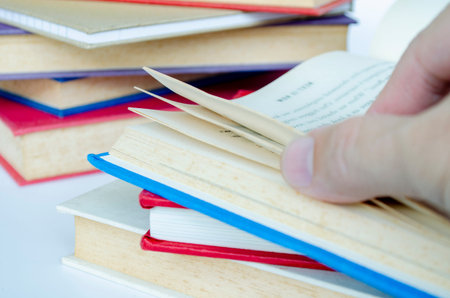 Fingers browsing layered books on desk with customizable space for text or ideas, illustrating study...
