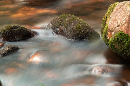Multiple exposure of a cold stream of water and moss covered rocks in a mountain creek. Captured in...