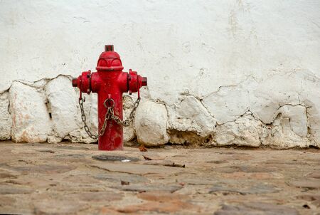 An old red fire hydrant in a stone paved street of the colonial town of Villa de Leyva, in the Andean mountains of central Colombia.の写真素材