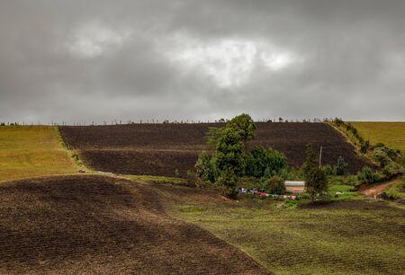 Multiple exposure of a typical farm house with some clothes drying outside, in the middle of different farmlands and some trees, in an overcasted day in the high mountains of the central Andes of Colombia.の写真素材