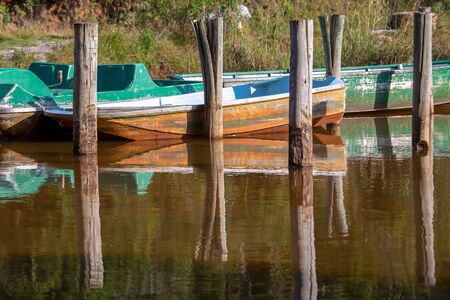 Some old boats and wooden posts on the water of the Las Coloradas lagoon, captured at sunset near...