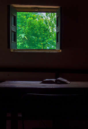An open book on a wooden table near a window in a farm house near the town of Arcabuco, in central...