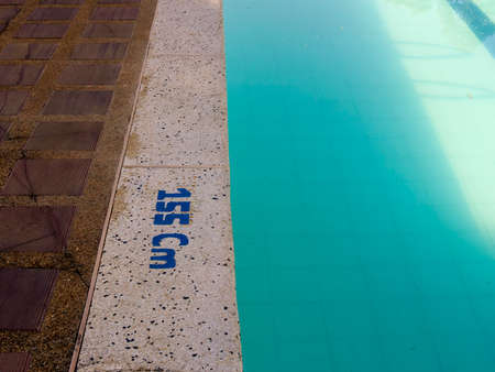 Close-up of the edge of a swimming pool in the morning, with the depth of the water written on the floor, in a country house near the town of Chinavita, in central Colombia.の写真素材