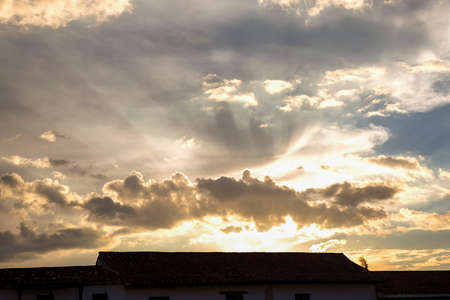 The silhouette of a colonial Spanish tile rooftop at the main square of the town of Villa de Leyva in the esatern Andes range of central Colombia, at sunset.の写真素材