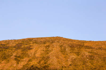 A clear blue sky behind a mountain illuminated by the light of sunset, near the colonial town of Villa de Leyva in central Colombia.の写真素材