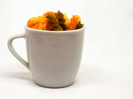 Studio shot of a heap of colorful raw fusilli pasta on a modern ceramic cup against neutral backgroundの写真素材