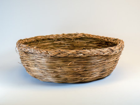Studio shot of a used traditional straw basket on a neutral backgroundの写真素材