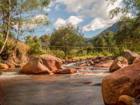 Long-exposure photography of the stream an the rocks of the El Valle river, with a rustic hanging...