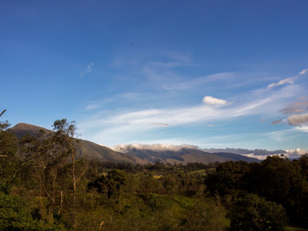 A mostly clear sky and soft clouds in the afternoon, over the farmlands in the eastern Andean...