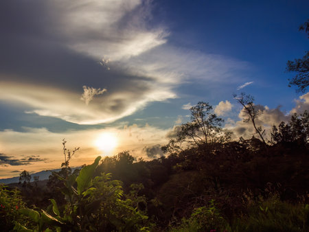 The sun behind an almost translucent cloud in the last minutes of the sunset, over the eastern Andean mountains of central Colombia.の写真素材