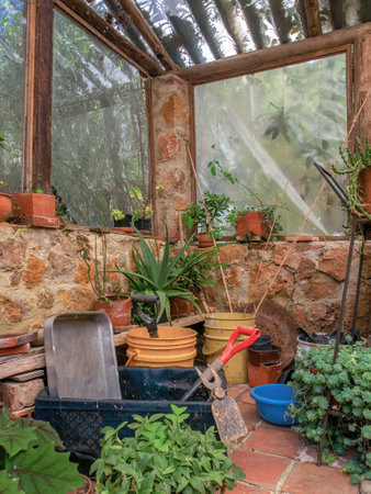 View of a rustic and deteriorated greenhouse with some plants and tools, in a farm near the colonial town of Villa de Leyva in central Colombia.の写真素材