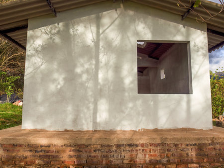 The light of the sunset casts the shadows of some trees on the white wall of a workshop in a farm near the town of Arcabuco in central Colombia.の写真素材