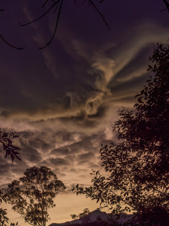 A big peculiar gray dense cloud hanging at sunrise over the farm lands of the eastern Andean mountains of central Colombia, before a rainstorm.の写真素材