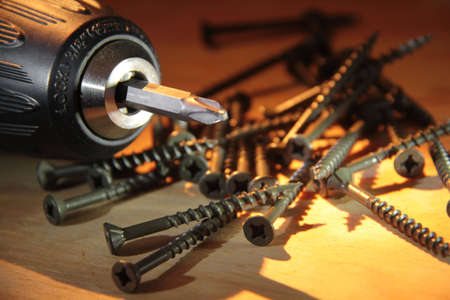 Electric drill and wood screws over lumber