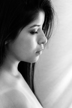 colorless portrait photo, latin woman with black hair and serious look, posing sideways to the left with white backgroundの写真素材