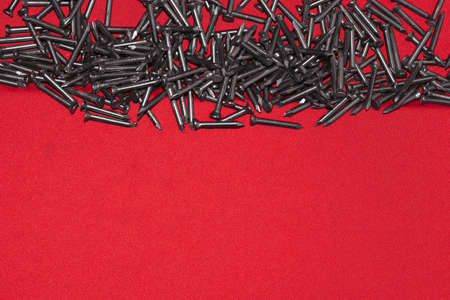 Black steel nails on wooden background, scattered randomlyの写真素材