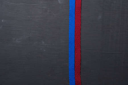 pair of blue and red shoelaces arranged vertically on black wooden backgroundの写真素材