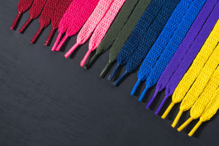 background of colored shoelaces on black wood, arranged diagonally, concept of perfection, leaving space for advertising textの写真素材