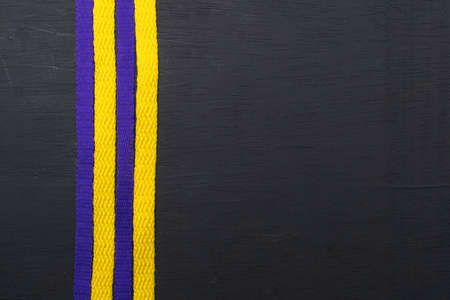 yellow and purple shoelaces, lakers flag, on black wooden background, leaving space for advertising...