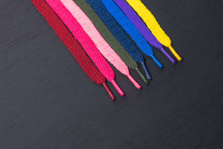 background of colored shoelaces on black wood, arranged diagonally, concept of perfection, leaving space for advertising textの写真素材