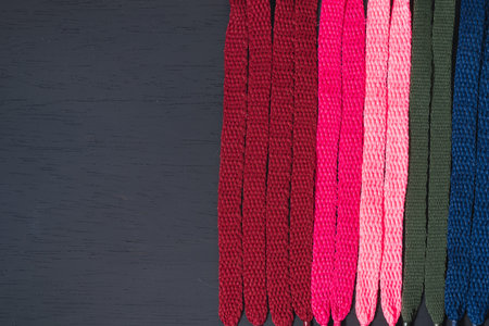 background of colored shoelaces on black wood, arranged vertically, concept of perfection, leaving space for advertising textの写真素材