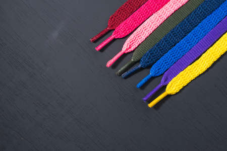 background of colored shoelaces on black wood, arranged diagonally, concept of perfection, leaving space for advertising textの写真素材