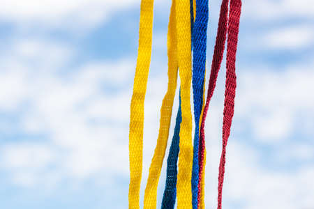 Flag of Colombia made with shoelaces, hanging on a background of the sky and cloudsの写真素材