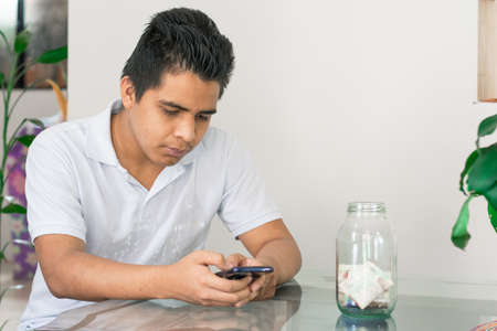 man doing online shopping, bad financial situation, guy texting on his mobile phone, banknotes on the table, bankrupt young man, spending his savings. economic conceptの写真素材