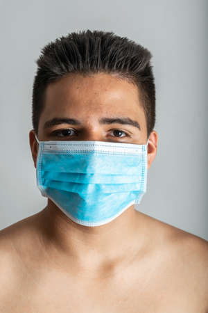 portrait of young latin man with surgical mask, shirtless, staring at the camera, Rembrandt lighting...