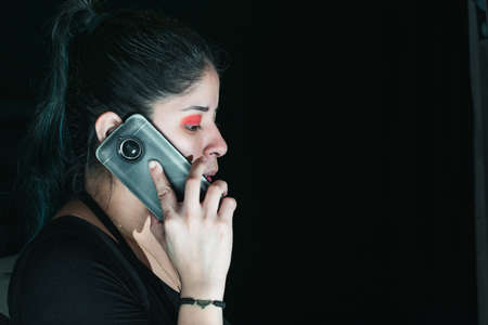 beautiful latina woman with green hair receiving a call, with her cell phone in her hand. with her...