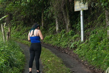 young latina woman lost on a trail, looking for directions to get out. girl standing on a path in the middle of the forest.の写真素材
