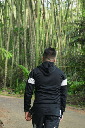 latin guy walking along a trail in the middle of a bamboo forest in colombia. beautiful jungle in south america, man walking in nature. ecology concept.の写真素材