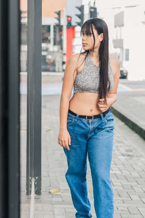 beautiful latina brunette woman standing next to a mirror on the street in the city of Pereira-Colombia. young woman admiring her beauty in the reflection of a clothing store.の写真素材