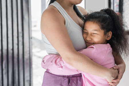beautiful and tender brown-skinned girl (latina) hugging her mother, with a happy face. daughter...