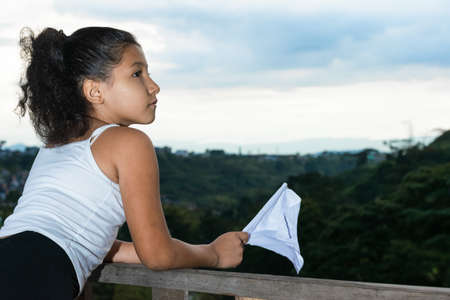 beautiful latina girl, brunette looking towards the horizon while waving her white flag (peace flag). girl with the hope of freedom and peace in her country full of war and massacres.の写真素材
