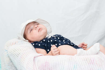 beautiful caucasian baby sleeping peacefully on a small cradle, dressed in a blue smock and a white hat. on a white background with space to copy text.の写真素材