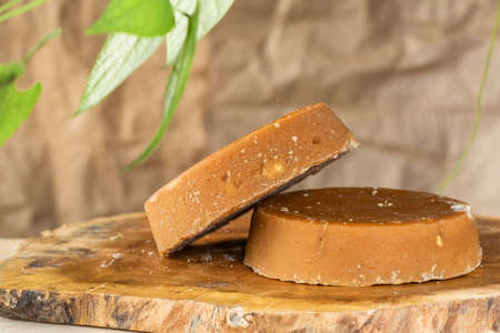 Colombian panela or sugar cane candy, ready to be consumed in various typical dishes. piloncillo ready for sale and marketing, placed on a wooden board and surrounded by green leaves.の写真素材